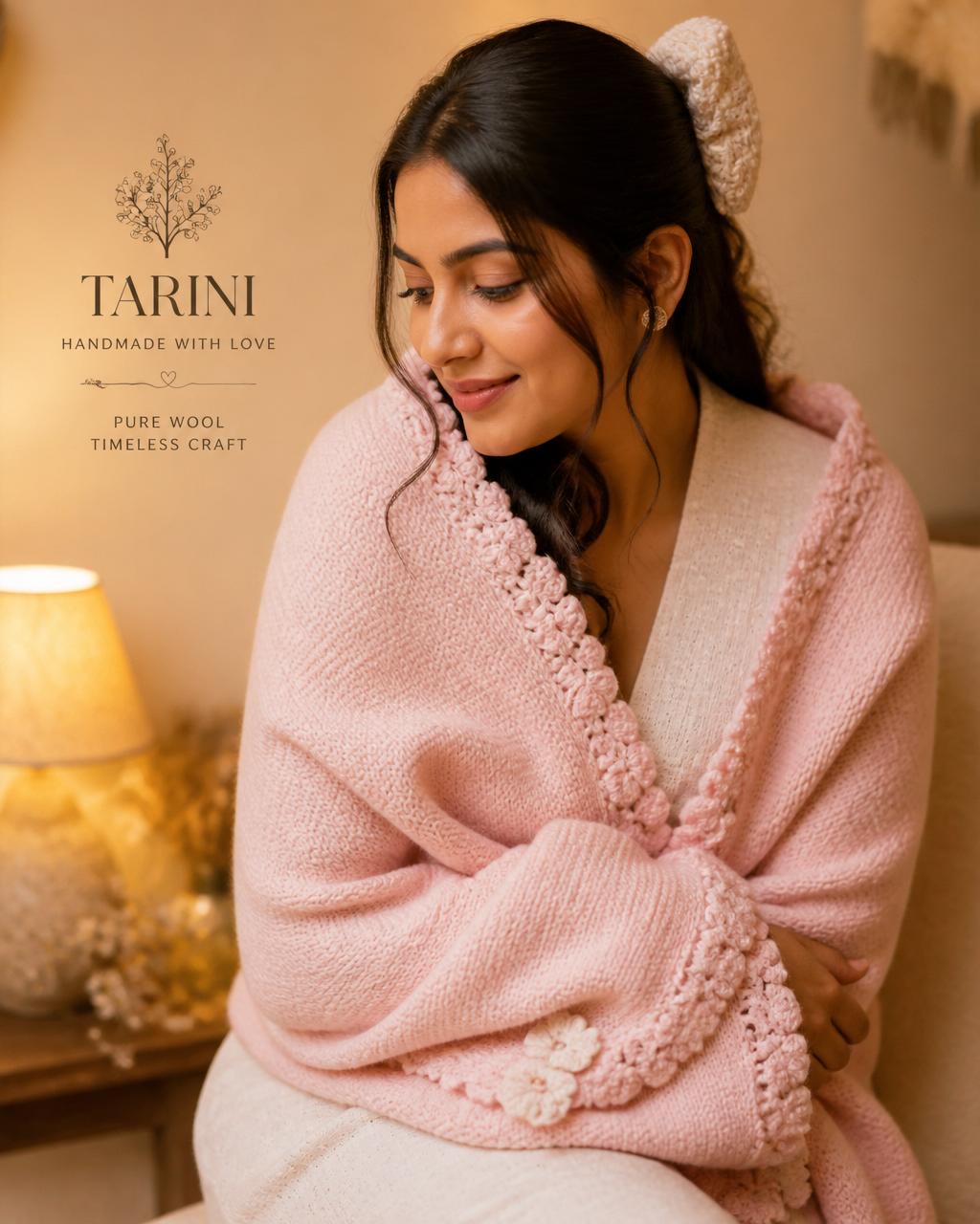 Stylish young woman wearing a pastel pink handmade woolen shawl with a cream wool bow
